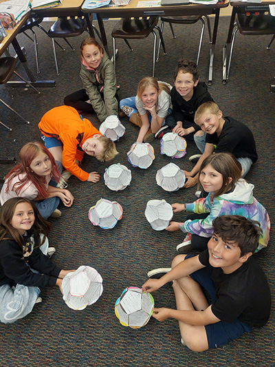 Children sitting in a circle with their paper bloom projects