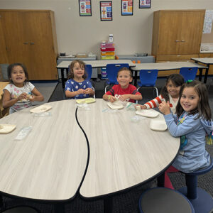 Table of students smiling while playing with clay