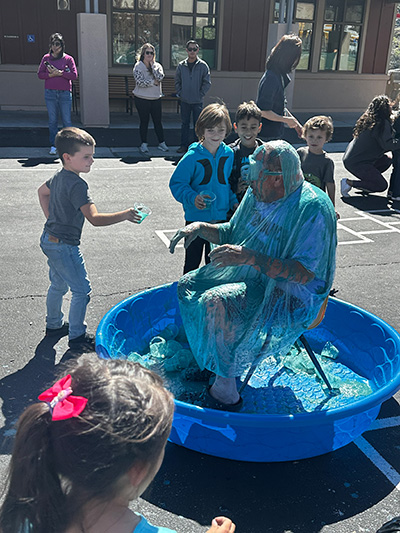 Children pouring slime on Principal McNelis