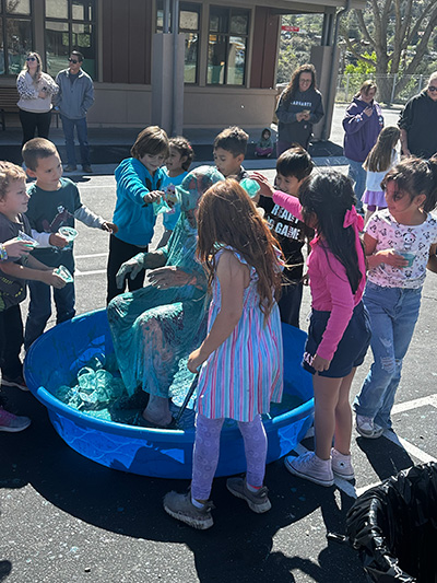 Children around Principal McNelis pouring slime on him
