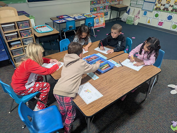 Students in pajamas coloring at tables