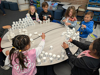 Students sitting around a table with stacks of plastic cups