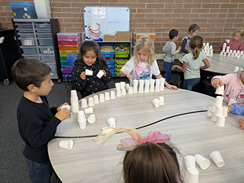 Students making different shapes out of stacked cups