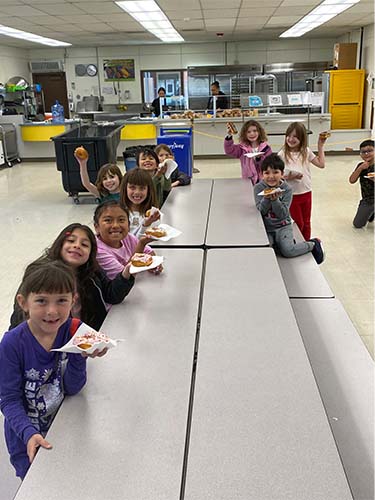 students at a table eating donuts
