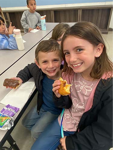 two students sitting eating donuts