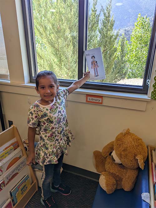 student pointing at her drawing in the window