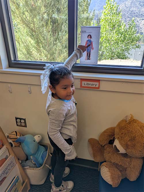 student pointing at her drawing in the window