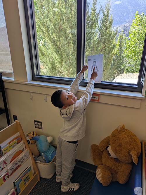 student pointing at his drawing in the window