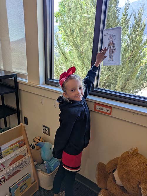 student pointing at her drawing in the window
