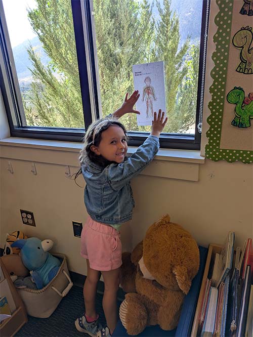 student pointing at her drawing in the window