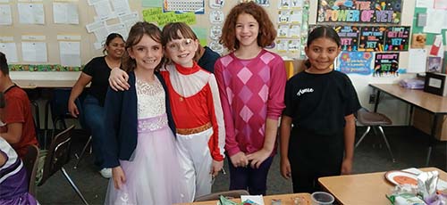 Four students hugging in costume