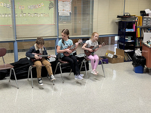 Three students enjoying their time playing ukuleles
