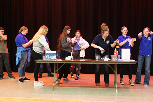 Teacher and students on stage preparing a science experiment