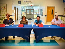Four welcoming staff members behind an information table