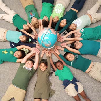 Students laying on the ground holding a globe