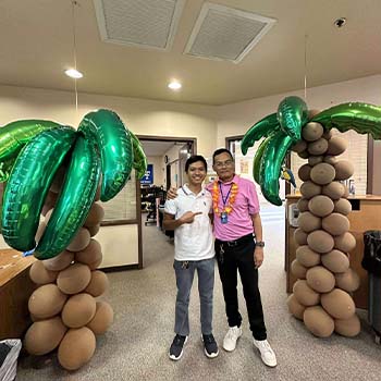 Two staff members between balloon palm trees
