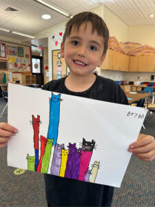 Boy holding up drawing of cats