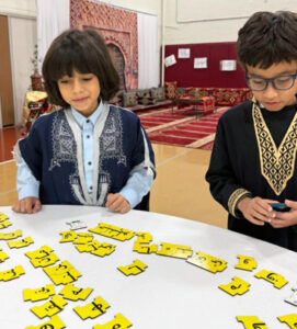 Two 3rd grade boys playing a game on a table on Arabic Day