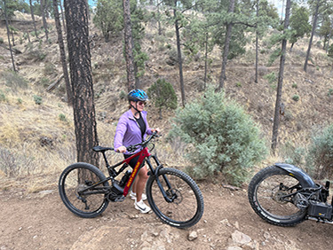 Student standing beside a bicycle in the trees