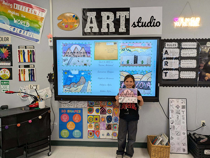 Happy elementary student holding up her Arizona Historical Society's Postcard